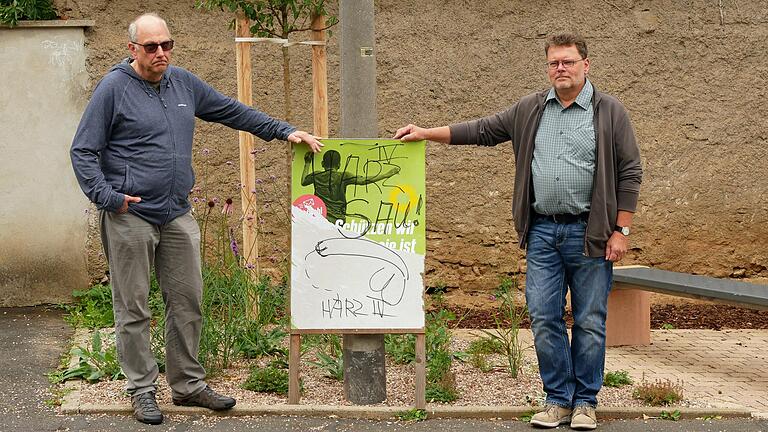 Rudolf Faatz (links) und Carsten Volkrodt sind für Bündnis 90/Die Grünen im Bergtheimer Gemeinderat ärgern sich, dass ein Teil ihrer Wahlplakate in Bergtheim (hier am Schimmelsplatz) unmittelbar nach dem Aufhängen beschmiert und zerstört wurde.