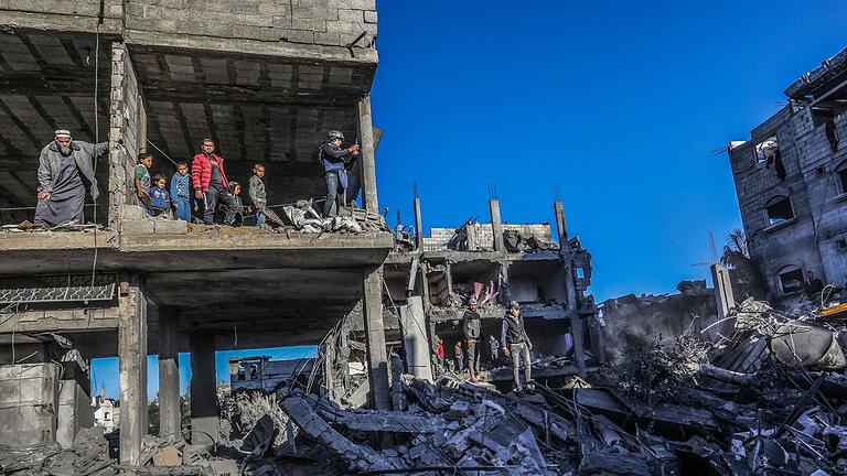 Zerstörung im Gazastreifen       -  Palästinenser inspizieren die Schäden nach einem israelischen Luftangriff in der Stadt Rafah. Nach dem Kriegsrecht müssen zivile Einrichtungen bei Angriffen möglichst verschont werden.