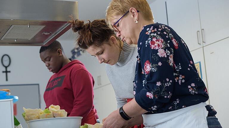 Gesund Kochen in der Kolpingschule       -  Zusammen mit Fachlehrerin Annette Oehler bereiten die Schüler Shana Rehm und Ebuka Odom in der Schulküche der Kolping-Schule am Heuchelhof Wraps zu. Die Mitarbeiter der Schülerfirma lernen nicht nur die Theorie zum Thema gesundes Essen, sondern sorgen für leckere Snacks, die sie in der Pause oder über Catering-Einsätze verkaufen.