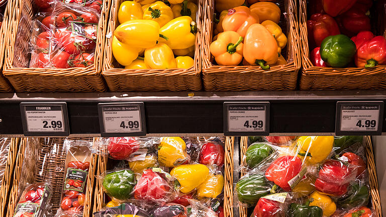 Verpacktes und loses Gemüse       -  In Plastik verpackte Paprika liegen in einem Supermarkt in Würzburg neben losen Paprika zum Verkauf aus.
