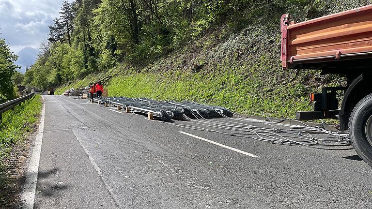 Die Teile des Schutzzauns liegen vorbereitet auf der Straße. Der Helikopter fliegt gefällte Bäume vom Hang aus und auf dem Rückweg Teile des Zauns an den Hang. Die Teile des Schutzzauns liegen vorbereitet auf der Straße. Der Helikopter fliegt gefällte Bäume vom Hang aus und auf dem Rückweg Teile des Zauns an den Hang.