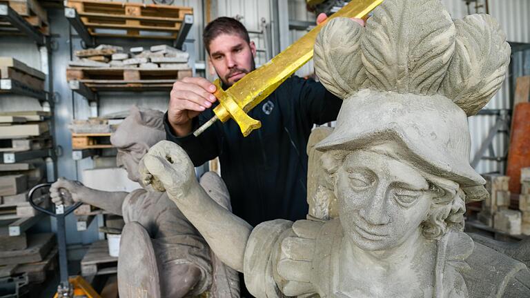 Nach der Restaurierung sollen die Engel der Mariensäule ihre vergoldeten Schwerter zurückerhalten. Steinmetz, Bildhauermeister und Restaurator Michael Rycek zeigt, wo sie eingesetzt werden.