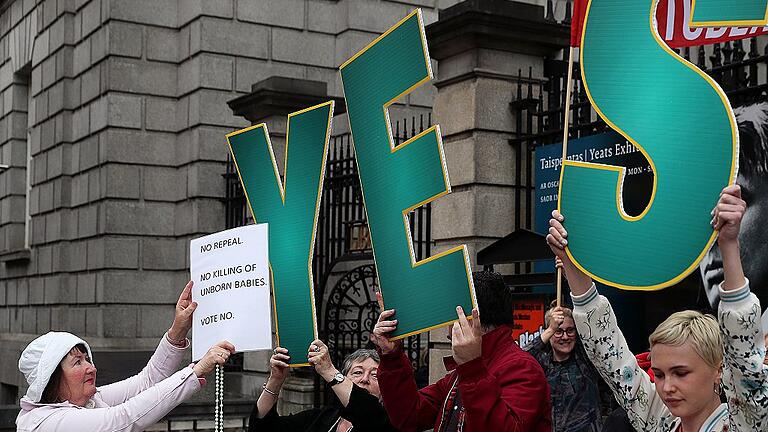 Referendum zu Abtreibungen in Irland       -  Eine Abtreibungsgegnerin (links) hält ein weißes Blatt vor das &bdquo;YES&ldquo; von Frauen, die Abtreibungen befürworten.