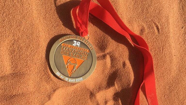 Die Auszeichnung für die Anstrengungen beim 'Marathon des Sables 2019': eine Medaille im Wüstensand Die Auszeichnung für die Anstrengungen beim 'Marathon des Sables 2019': eine Medaille im Wüstensand