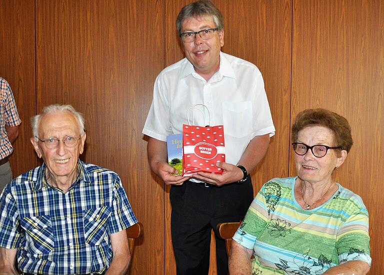 Pfarrer Amrehn überreicht ein Geschenk an Lotte Hetterich, die Frau des scheidenden Leiters des Seniorenkreises Gernach. Links: Hugo Hetterich