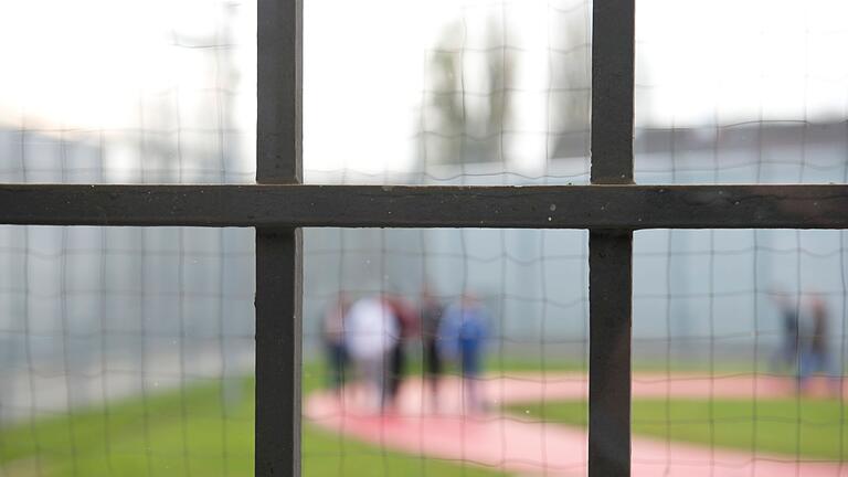 Gefängnis       -  Hinter einem Gitter laufen Gefängnisinsassen über einen Gefängnishof.