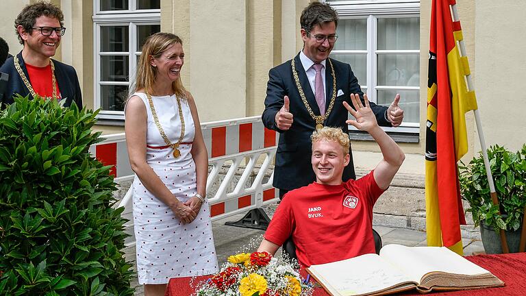 Kickersspieler Luke Hemmerich beim Eintrag ins Goldene Buch der Stadt Würzburg. Die Bürgermeister Martin Heilig, Judith Jörg und Oberbürgermeister Christian Schuchardt freuen sich mit der Mannschaft.
