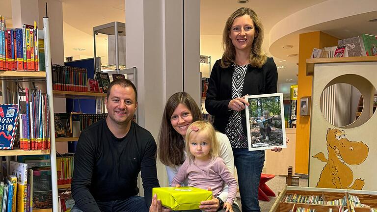 Familie Hümmer (Christoph, Teresa mit Klara) freut sich mit der Bibliotheksleitung Sylvia Büttner über den Hauptgewinn des Fotowettbewerbs 'Ein BIZ-Buch auf Reisen'.