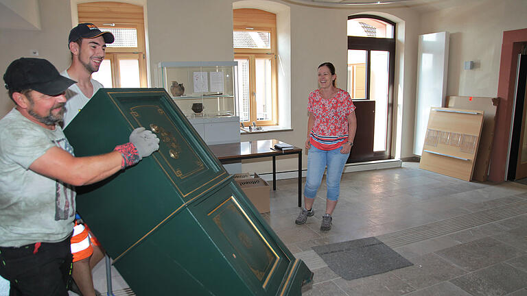 Beobachtet von Bürgermeisterin Andrea Rothenbucher wuchten zwei kräftige Mitarbeiter des Bauhofs auf einer Sackkarre den historischen Tresor der Gemeinde Hettstadt über den noch provisorischen Zugang ins gerade sanierte Rathaus.