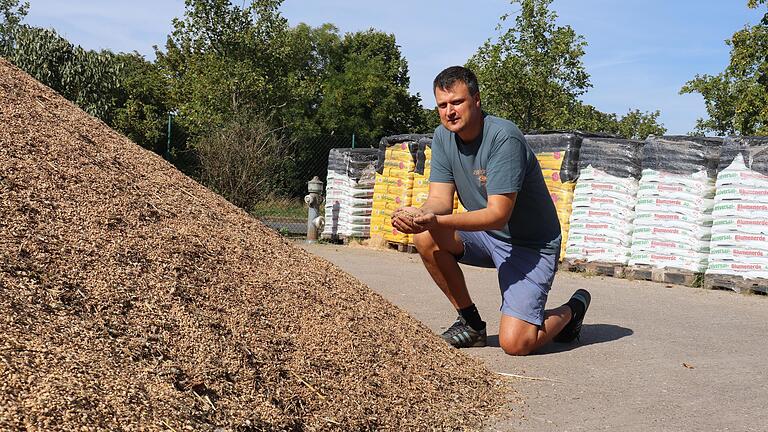 Mathias Schulz kniet vor einem Berg Weizen, der mitten auf seinem Firmengelände in Wiesentheid liegt. Der Unternehmer braucht dringend mehr Lagerfläche für das angelieferte Getreide.&nbsp;