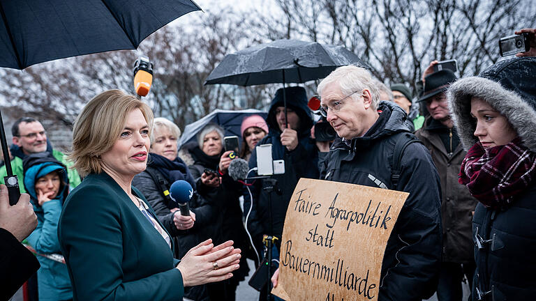 Spitzentreffen zu Lebensmittelpreisen       -  03.02.2020, Berlin: Julia Klöckner (CDU), Bundesministerin für Ernährung und Landwirtschaft, steht vor einem Mann, der ein Plakat mit der Aufschrift «Faire Agrarpolitik statt Bauernmilliarde» und spricht mit Aktivisten der «Arbeitsgemeinschaft bäuerliche Landwirtschaft» und der Umweltschutzorganisation Greenpeace vor dem Bundeskanzleramt. Im Streit um Lebensmittelpreise im Supermarkt beraten bei einem Spitzentreffen Vertreter des Einzelhandels und der Lebensmittelindustrie, mit Kanzlerin Merkel, Agrarministerin Klöckner und Wirtschaftsminister Altmaier über Lösungen. Foto: Michael Kappeler/dpa +++ dpa-Bildfunk +++