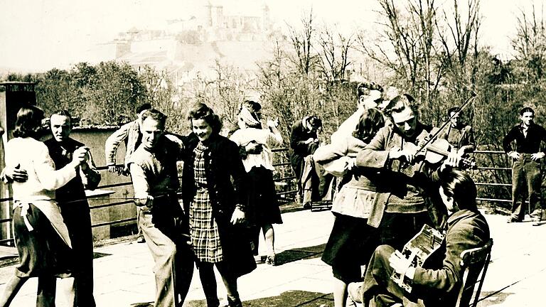 Am 21. April 1945 nahm ein amerikanischer Agenturfotograf auf der Dachterrasse des Studentenhauses am Sanderrasen dieses Foto von tanzenden und musizierenden ehemaligen Zwangsarbeiterinnen und Zwangsarbeitern auf. Weil der spätere Nazi-Propagandaminister Joseph Goebbels im Wintersemester 1919/20 in Würzburg studiert hatte, trug das Haus seit 1937 seinen Namen.&nbsp;