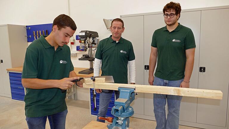 Im neuen Ausbildungszentrum der Bayerischen Staatsforsten in Arnstein ist alles Notwendige an Technik und Geräten vorhanden. Auszubildender Christian Hartmann arbeitet mit Holz und Säge. Daneben Ausbildungsleiter Anton Lotter und Jakob Geiger.