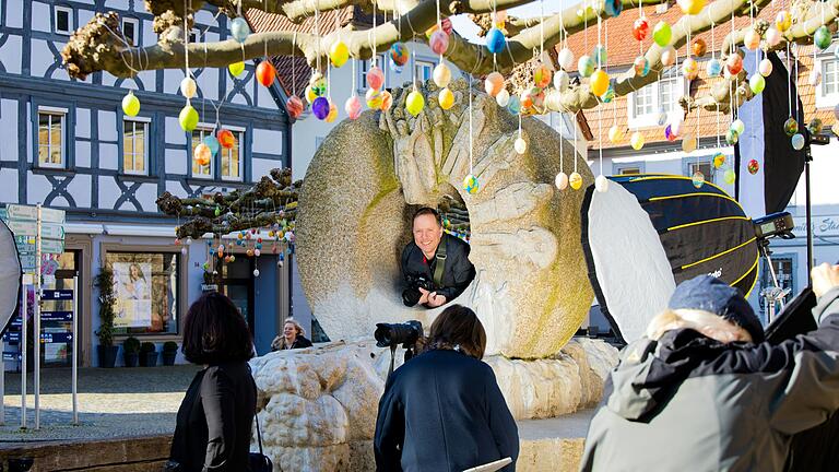 Sebastian Schaar, Mitglied des Gerolzhöfer Fotostammtisch posiert gerade testweise am Gerolzhöfer Brunnen am Marktplatz. Andere Stammtischler rücken die richtige Beleuchtung für das gemeinsame Gruppenfoto zurecht.