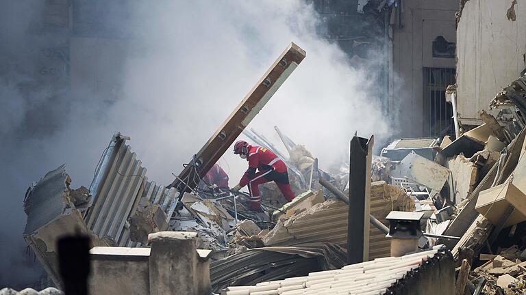 dpa_5FAD120076570DBF.jpg       -  Ein Bagger räumt die Trümmer eines eingestürzten Gebäudes weg, während Feuerwehrleute nach Verschütteten suchen.