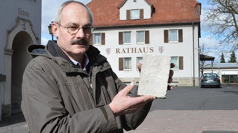 Dieser Muschelkalk-Belag, den Bürgermeister Fridolin Zehner zeigt, gefiel den Ratsmitglieder auf ihrer Rundfahrt recht gut, als sie in Strahlungen vor der Kirche Halt machten. Jetzt soll er den neuen Kirch-/Schulplatz in Rannungen zieren.