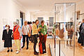 Besucherinnen und Besucher der Vernissage betrachten sowohl Gemälde als auch Plastiken