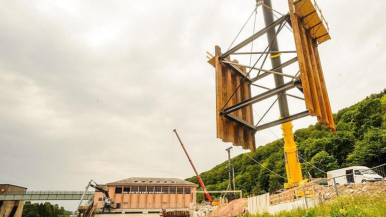 Mit Hilfe von neun Elementen wird die Baustelle trocken gelegt und gehalten: Ein Autokran hievt eines davon für den Fangedamm in den Main.