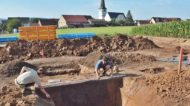 1,60 Meter tief ist diese Grube, die vor einigen Tagen bei Großeibstadt freigelegt wurde. Ob es ein Brunnen oder eine Abfallgrube war, ist noch ungewiss, sagt Grabungsleiterin Marlene Ruppert-Dallmann. Sie vermisst mit einem Mitarbeiter die Grube.