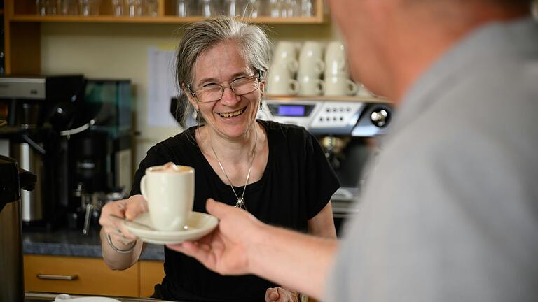 Eine Mitarbeiterin serviert im Café Perspektive am Waldkugelweg in Würzburg einen Cappuccino.