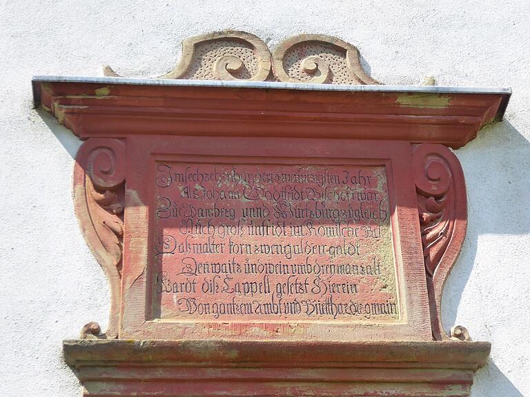 Die Inschrift  über dem Seiteneingang kündet vom Baubeginn des Kirchengebäudes im Jahre 1620.