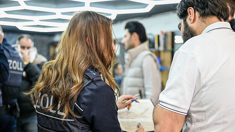 Eine Zollbeamtin stellt einem Barbershop Mitarbeiter in Würzburg verschiedene Fragen zu seiner Beschäftigung in dem Betrieb. Eine Zollbeamtin stellt einem Barbershop Mitarbeiter in Würzburg verschiedene Fragen zu seiner Beschäftigung in dem Betrieb.