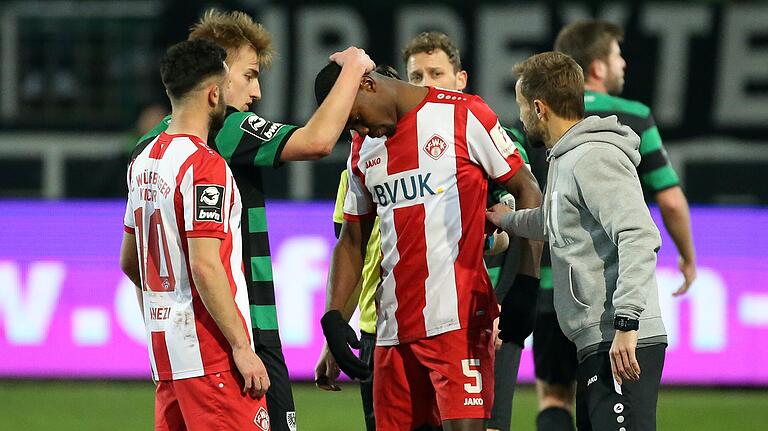 Albion Vrenezi, Münsters Simon Scherder (von links) und Kickers-Trainer Michael Schiele (rechts) trösten Leroy Kwadwo, der von einem Münsteraner Zuschauer mit Affenlauten rassistisch beledigt wurde.