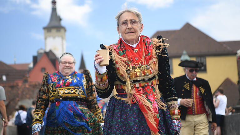 Fränkische Tracht und moderner Pappbecher: Traditon und Moderne beim Würzburger Kiliani-Umzug.