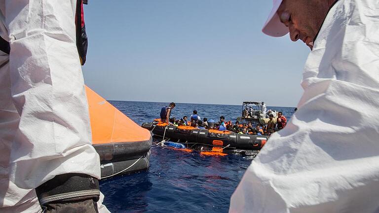 Flüchtlingsboot kentert vor Libyen       -  Gerettet: Überlebende des gekenterten Flüchtlingsbootes werden auf Rettungsboote geholt. Die Organisation Ärzte ohne Grenzen übernahm die Erstversorgung der Menschen.