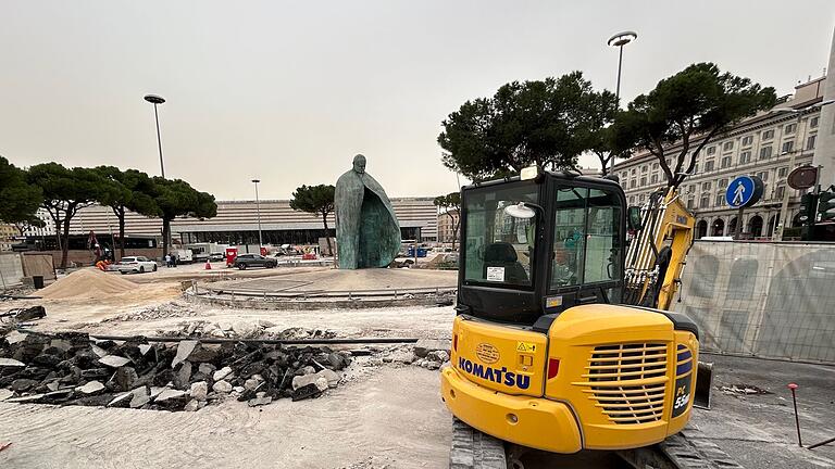 Baustelle in Rom       -  Der bronzene Papst Johannes Paul II. vor dem Hauptbahnhof blickt auf einen aufgerissenen Boden.