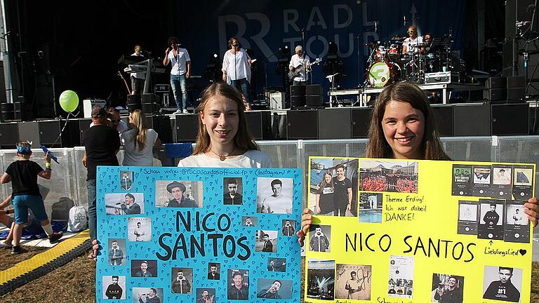 Amelie Schemmel und Amelie Hart sind extra aus dem Landkreis Schweinfurt nach Marktheidenfeld gekommen, um Nico Santos zu sehen. Pünktlich zum Beginn des Vorprogramms waren sie auf dem Festivalgelände, um sich Plätze direkt vor der Bühne zu sichern. Im Hintergrund spielt schon die Bayern-3-Band. Amelie Schemmel und Amelie Hart sind extra aus dem Landkreis Schweinfurt nach Marktheidenfeld gekommen, um Nico Santos zu sehen. Pünktlich zum Beginn des Vorprogramms waren sie auf dem Festivalgelände, um sich Plätze direkt vor der Bühne zu sichern. Im Hintergrund spielt schon die Bayern-3-Band.