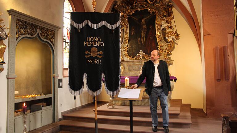Pfarrer Sven Johannsen mit der Homo-memento-mori-Fahne in St. Michael. Sie soll laut Johannsen nicht Weltuntergangsstimmung verbreiten, sondern daran erinnern, dass viele Generationen ihr Vertrauen und ihre Hoffnung aus dem Glauben an Gott geschöpft haben.