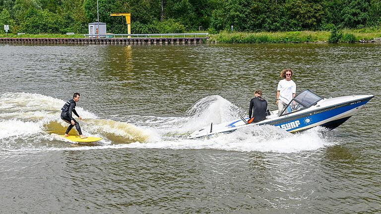 Julian Piller steuert das Boot, während Jonathan Schröter sich auf dem Surfbrett ausprobiert.