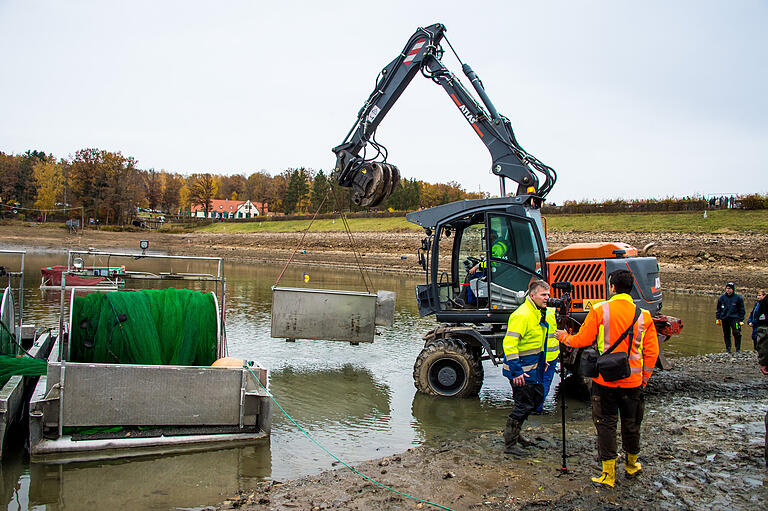 Ein Bagger hob große Behälter ins Wasser, mit denen die gefangenen Fische zur Verladung in Spezialtransportboxen auf die Lastwagen am Ufer gebracht wurden. Ein Bagger hob große Behälter ins Wasser, mit denen die gefangenen Fische zur Verladung in Spezialtransportboxen auf die Lastwagen am Ufer gebracht wurden.