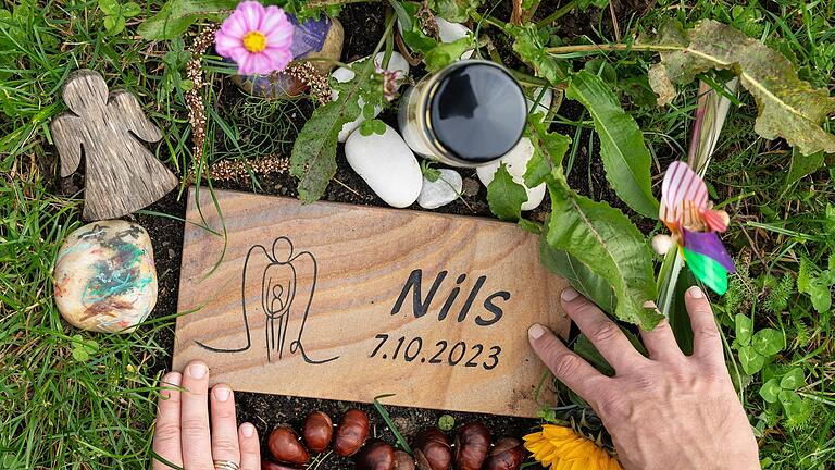 Die kleine Platte mit der Aufschrift 'Nils' haben Michael und Maria neben die Stele für Sternenkinder auf dem Volkacher Friedhof gelegt. Die kleine Platte mit der Aufschrift 'Nils' haben Michael und Maria neben die Stele für Sternenkinder auf dem Volkacher Friedhof gelegt.