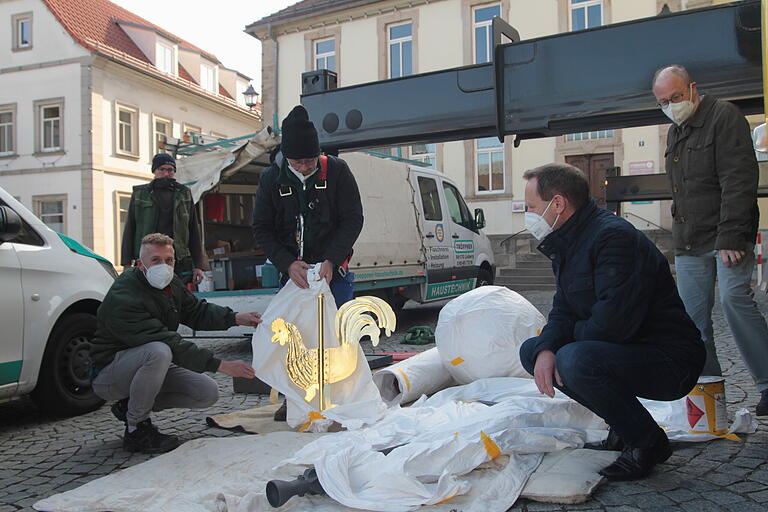 Noch verpackt am Boden sind Kreuz, Turmkugel und der goldene Hahn mit (von links) Rainer Reitz, Zimmermeister Tomas Bauerschmitt, Spenglermeister Alfred Tröppner,&nbsp; Bürgermeister Michael Ziegler und Stadtarchivar Thomas Schindler.