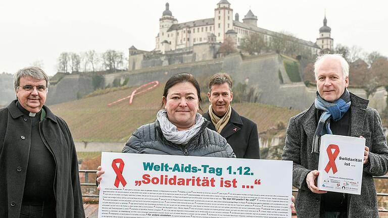 Zum Welt-AIDS-Tag hat die Caritas Unterfranken die rote AIDS-Schleife am Festungsberg installiert, zum Zeichen der Solidarität. Mit dabei waren Heidrun Brand (Mitte), Würzburgs Oberbürgermeister Christian Schuchardt (hinten), Clemens Bieber (links) und Dieter Wenderlein von Sant´Egidio (rechts).