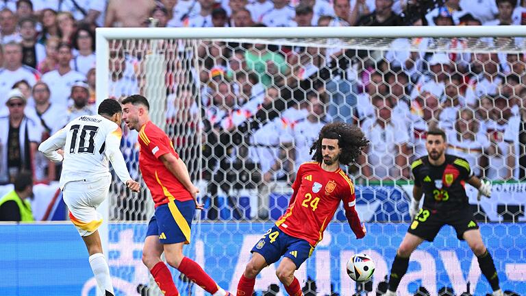 Euro 2024: Spanien - Deutschland       -  Spaniens Marc Cucurella (M) bekommt den Schuss von Deutschlands Jamal Musiala an den Arm.