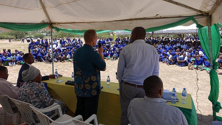 Dr. Andreas Müller erläutert Schülern und Multiplikatoren im Distrikt Magu die Hintergründe des Projekts zur Bekämpfung der Schistosomiasis. Zusätzlich anwesend sind weitere politische Ehrengäste aus der Stadt Mwanza und dem Distrikt Magu, sowie der medizinischen Direktor des Distrikts.