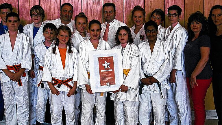 Zertifikat für die Judoabteilung des 1. FC Iphofen       -  (zis)   Die Judoabteilung des 1. FC Iphofen erhält das Vereins-Zertifikat des Deutschen Judobundes. Das Zertifikat bestätigt Judovereinen/Judoabteilungen, dass sie Mitglied im Deutschen Judo-Bund e.V. und dem zugehörigen Landesverband sind. Das Vereins-Zertifikat wurde für die Jahre 2012 &ndash; 2015 verliehen, sofern gewisse Standards innerhalb des Vereins oder der Abteilung gegeben sind, teilt der FC Iphofen in einem Presseschreiben mit. Die erforderlichen Qualitätskriterien sind: qualifizierte Judotrainer, Dan-Träger im Verein, Kyu&ndash;Prüfungen nach DJB Richtlinien, regelmäßige Breitensportaktionen sowie die Teilnahme am Wettkampfbetrieb. Das Vereins-Zertifikat sichere einen Grundstandard in den Vereinen, so das Schreiben weiter. Außerdem sollen mit dem Vereins-Zertifikat Personen, die den Verein aktiv oder passiv unterstützen, gewürdigt werden. Neben den Trainern Manja und Sven Vaegler und Harald Haberkamm hat die Judoabteilung des 1. FC Iphofen nun die erste Trainerin aus eigenen Reihen: Dominice Weiglein hat 2012 den Fach-Übungsleiter Judo absolviert. Im Bild (hinten von links): Max Haberkamm, Jakob Bode, Harald Haberkamm (Trainer Breitensportgruppe), Nicola Weiglein (Trainerin Wettkampf), Frank Kristinus (FC-Vorsitzender), Dominice Weiglein (Trainerin Wettkampfgruppe), Arne Müller, Oliver Zink, Claudia Zink, Ulrike Weiglein (beide Abteilung Judo), (vorne von links): Leon Burkholz, Hannes Haberkamm, Tarah Müller, Lia-Kim Nett, Paula Kasper und Manuel Schlee.