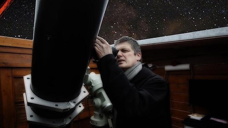 Pater Christoph am Teleskop. Der im Hintergrund zu sehende Sternenhimmel ist in das Foto montiert worden.