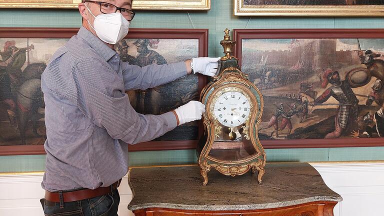 Das Foto zeigt den Restaurator Michael Bronold bei der Aufstellung der Uhr im Bilderzimmer.