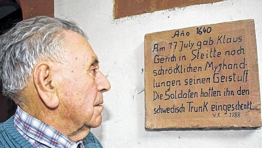 Aktiver Senior: Edmund Höfling nimmt mit seinen 90 Jahren noch sehr aktiv am Dorfleben in Stetten teil. Hier blickt er auf eine Tafel an seinem Haus, die auf ein schicksalhaftes Ereignis während des Dreißigjährigen Krieges hinweist.