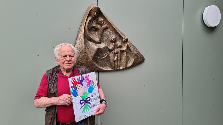 Peter Vollert neben seiner Schutzmantelmadonna und dem Geschenk der Kinder des Kindergartens Üchtelhausen.