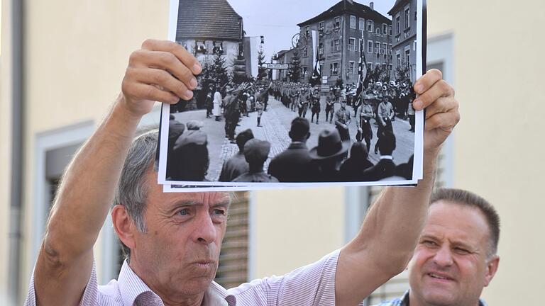 Am Platz vor der Sparkasse zeigte Bernd Göbel, Vorsitzender des Historischen Vereins Markt Werneck,&nbsp; das Foto eines Aufmarschs in der damaligen Adolf-Hitler-Straße, der heutigen Schönbornstraße.