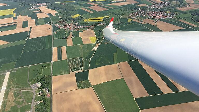 Die Tragfläche ragt in die Aussicht auf die Dörfer und Felder in der Umgebung des Flugplatzes Giebelstadt. Charakteristisch für Segelflieger: eine hohe Spannweite der Flügel. Bei diesem Duo Discus D-2376 sind es 20 Meter zwischen den beiden Flügelspitzen. Die Tragfläche ragt in die Aussicht auf die Dörfer und Felder in der Umgebung des Flugplatzes Giebelstadt. Charakteristisch für Segelflieger: eine hohe Spannweite der Flügel. Bei diesem Duo Discus D-2376 sind es 20 Meter zwischen den beiden Flügelspitzen.