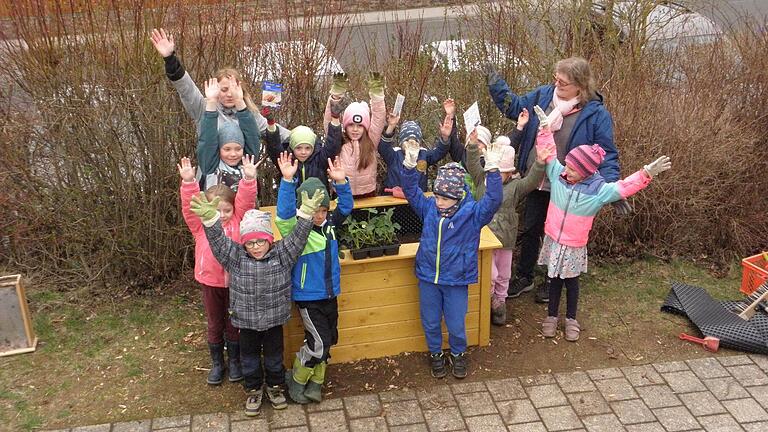 Geschafft! Das Hochbeet ist fertig befüllt und kann bepflanzt werden. Fröhlich winken die Kinder zum Abschluss.