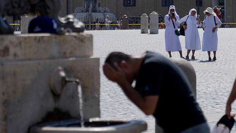 Hitze in Italien       -  Ein Mann erfrischt sich an einem Brunnen auf dem Petersplatz, während die Temperaturen bis zu 38 Grad Celsius im Vatikan erreichen.