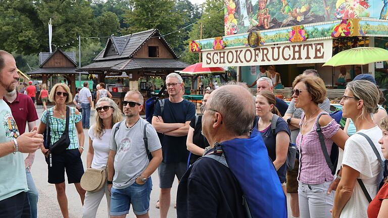 Die Teilnehmenden der Backstage-Tour auf der Laurenzi-Messe interessieren sich für das Leben der Schausteller und deren Fahrgeschäfte. Unter anderem Eric Dietz, der das Laufhaus 'Rio' betreibt, steht Rede und Antwort.