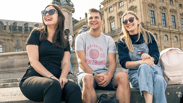 Studierende der JMU vor der Würzburger Residenz. In dem früher fürstbischöflichen Schloss und UNESCO-Welterbe sind unter anderem Philosophie-Lehrstühle und die Altertumswissenschaften der Universität zu Hause.